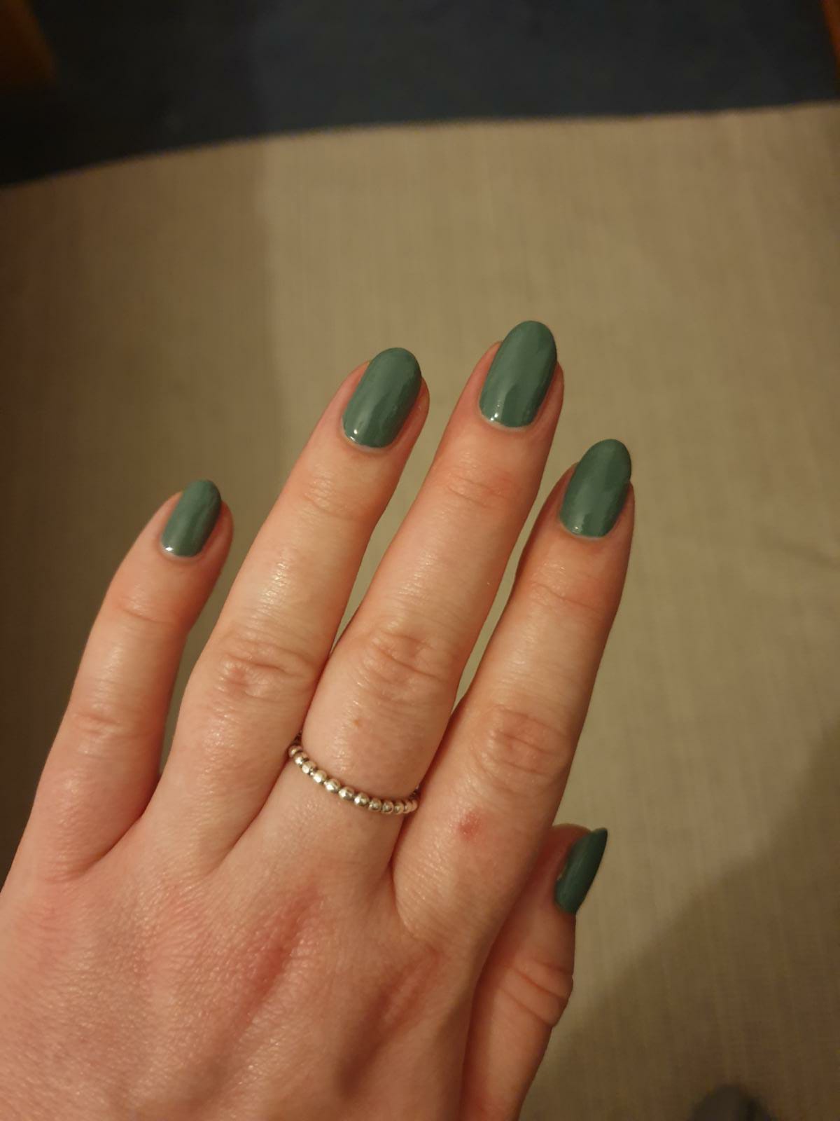 Swatch of olive green nail polish on nails.