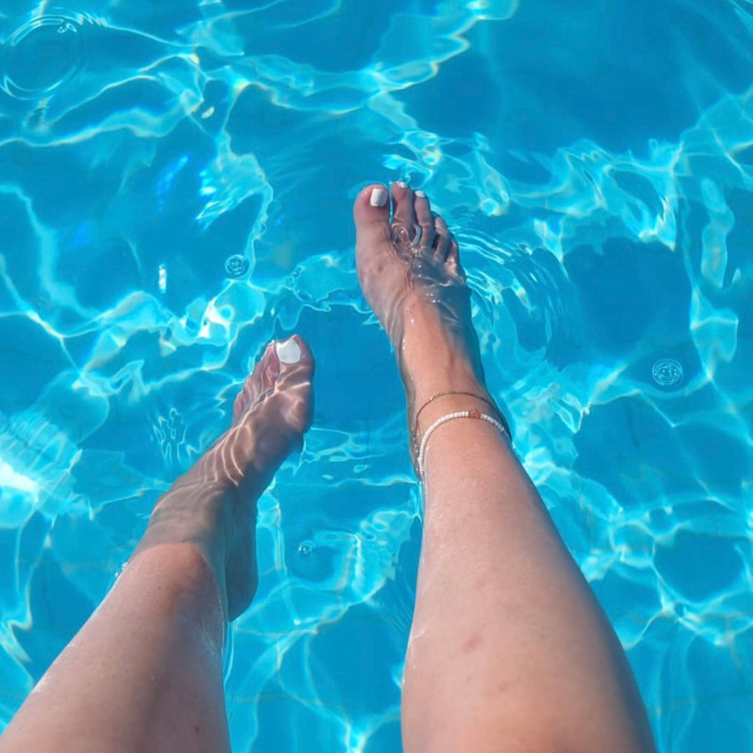 white nail polish pedicure, in clear blue water on holiday (in pool).